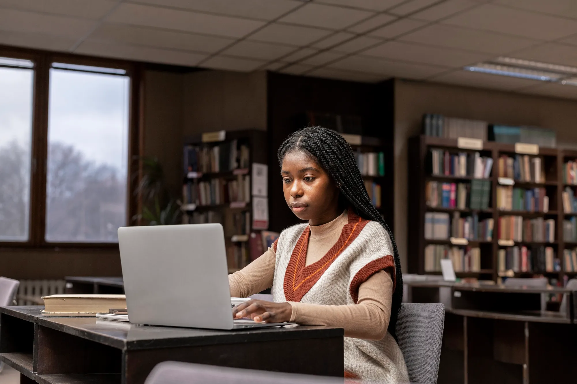 Estudante a trabalhar num computador portátil na biblioteca.